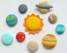 small felt planets are arranged on a white surface