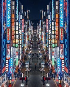 an aerial view of a city at night with many signs on the buildings and people walking down the street