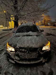 a car covered in snow parked next to a tree