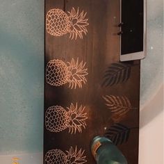 a bottle of wine sitting on top of a wooden plaque with pineapples drawn on it