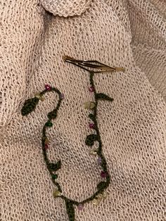 a close up of a necklace on a white cloth with beads and leaves hanging from it