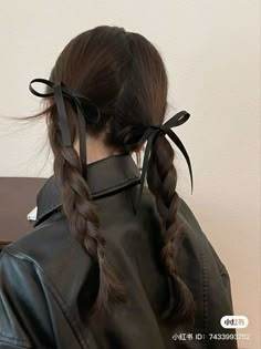 a woman wearing a black leather jacket with two braids in her hair, looking off to the side