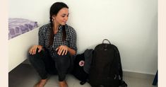 a woman sitting on the floor next to a backpack