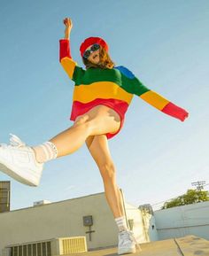 a woman in a colorful dress and hat is doing a trick on a skateboard