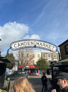 people are walking under the camden market sign on a sunny day in london, england