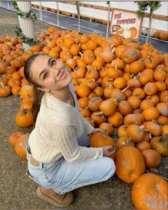 a woman sitting on the ground surrounded by pumpkins