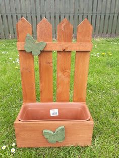 a wooden chair sitting in the grass with a planter on it's back