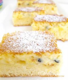 four pieces of cake on a plate with powdered sugar and blueberry toppings