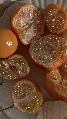 some oranges that have been cut in half on a white plate with gold glitter