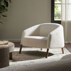 a white chair sitting on top of a rug next to a window