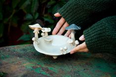 a person holding a bowl with mushrooms on it and two small white bowls in front of them