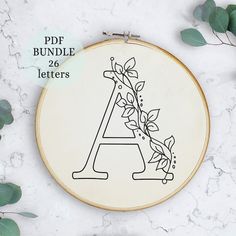 an embroidery pattern with the letter a in it and leaves around it on a marble surface