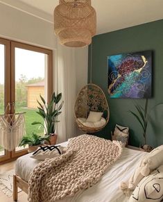 a bedroom with green walls and white bedding, hanging chair, potted plant and wicker hammock