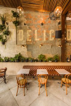 the inside of a restaurant with tables, chairs and potted plants on the wall