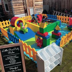 an inflatable play area with lots of blocks and toys on the grass next to a wooden fence