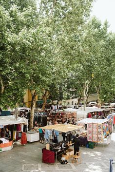 an outdoor market with tents and tables under trees