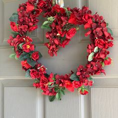 a wreath with red flowers hanging on the front door