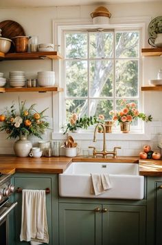 a kitchen with green cabinets and wooden counter tops, an open window above the sink