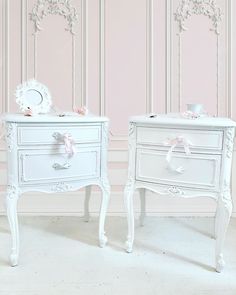 two white nightstands with pink bows on the top and bottom, against a pink wall