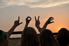 several people are holding their hands up in the air at sunset or sunrise, while the sun is setting