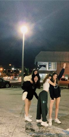 three girls standing in the middle of a parking lot with their arms around each other