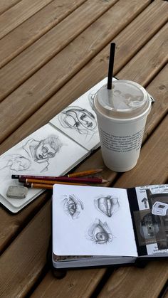 a coffee cup sitting on top of a wooden table next to a book and pencils