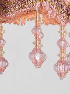 a pink chandelier hanging from the ceiling with beaded trimmings on it