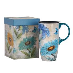 a blue and white coffee mug with flowers on it next to a box that is open