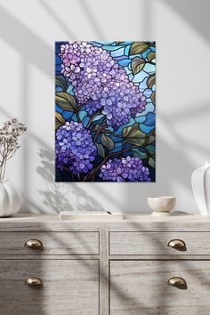 a painting of purple flowers on a blue background in a room with drawers and vases