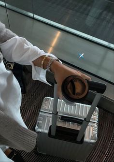 a woman holding onto a piece of luggage with her hand on top of the suitcase