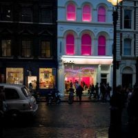 a group of people standing in front of a building at night with the lights on