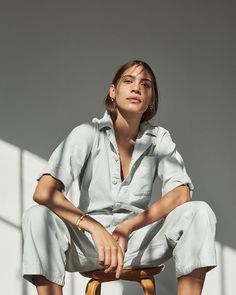 a woman sitting on top of a wooden stool