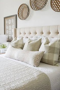 a bed with white sheets and pillows on top of it next to three wall hangings