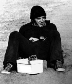 a man sitting on the ground next to a white box