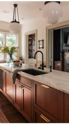 a kitchen with marble counter tops and dark wood cabinetry, along with hanging lights