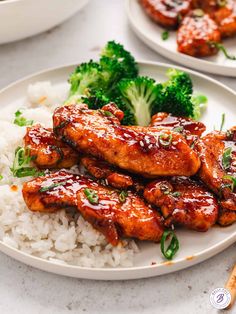 two plates filled with chicken and broccoli covered in sauce next to white rice