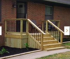 a wooden deck with steps and railings in front of a brick building