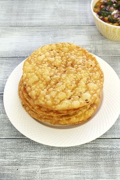 three cookies sitting on top of a white plate next to a bowl of beans and sauce