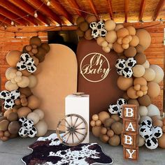 a baby shower is decorated with balloons and cow - print decorations, including a wagon