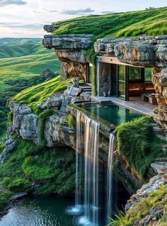 a house built into the side of a cliff with a waterfall coming out of it