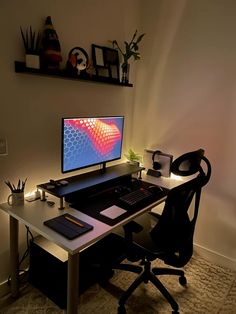 a desk with a computer monitor and keyboard sitting on top of it next to a plant