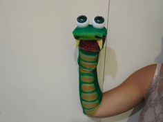 a woman holding up a fake snake head on the wall next to a white wall