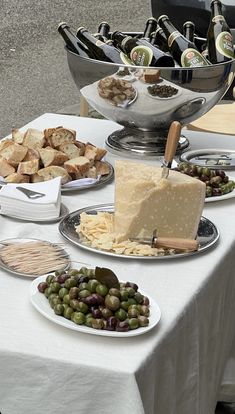 a table topped with plates of food next to bottles of wine and cheeses on trays