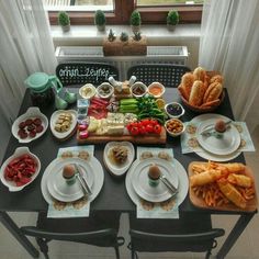 a table filled with plates and bowls of food next to a window in a room