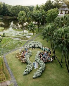 an aerial view of a wedding ceremony in the middle of a lush green area with palm trees