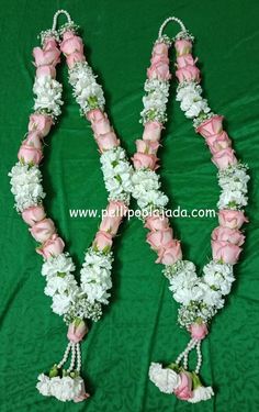 two pink and white flower leis on a green tablecloth with flowers in the middle