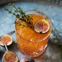 a glass filled with liquid and sliced figs on top of a metal platter