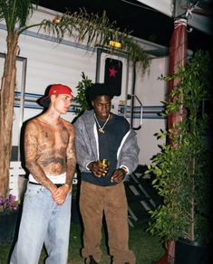 two young men standing next to each other in front of a building with palm trees