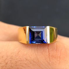 a close up of a person's hand wearing a ring with a blue and green stone