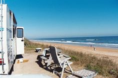 an rv parked on the beach next to picnic tables